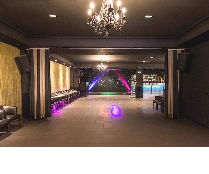 Sala Black en Barcelona, salón oscuro con lámpara de araña, cortinas doradas, taburetes iluminados y pista de baile con telón de estrellas