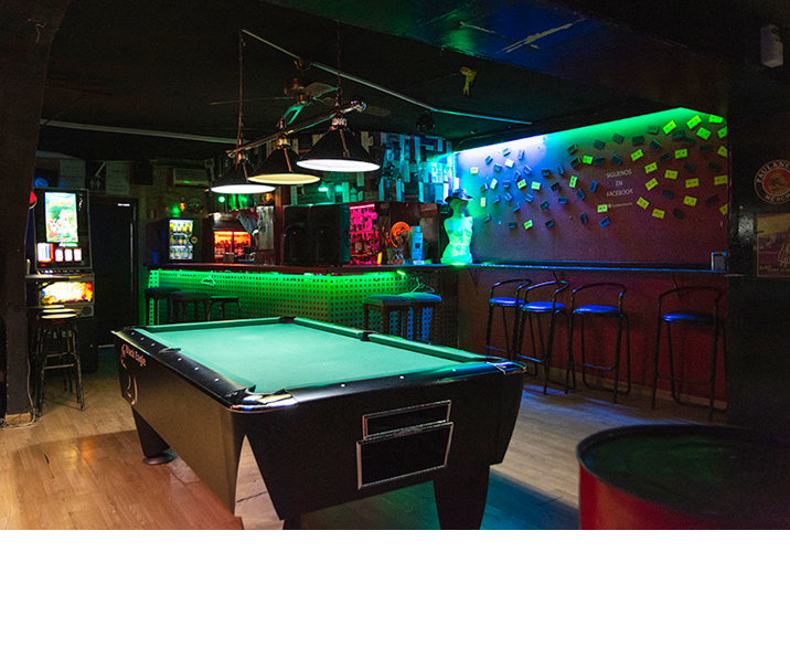 Sala Red en Barcelona, bar con mesa de billar, barra iluminada en verde, taburetes altos y ambiente de pub
