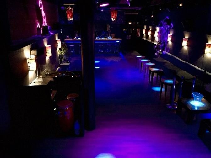 Sala Aqua Altos en Barcelona, discoteca privada con iluminación azul y morada, barra al fondo, taburetes altos y pista de baile despejada